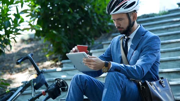 Bearded Businessman Sitting On Stairs And Using Digital Tablet alt