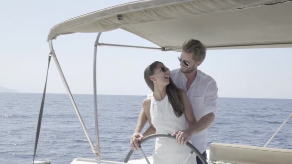 Couple Steering Their Yacht Together Slow Motion alt