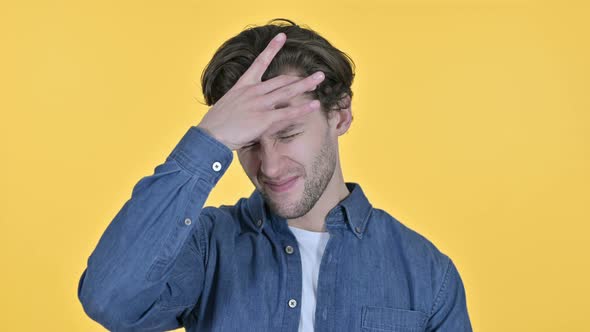 Young Man Having Headache, Pain in Head on Yellow Background alt