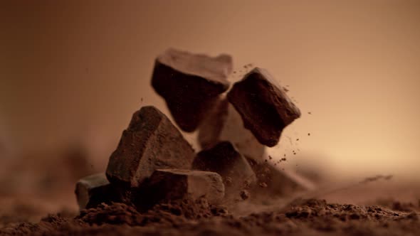 Super Slow Motion Shot of Raw Chocolate Chunks Falling Into Cocoa Powder at 1000Fps. alt