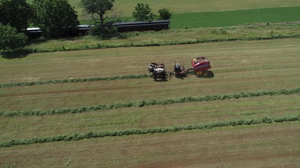 View of an Amish Farmer Harvesting His Crop with 4 Horses and Modern Equipment alt