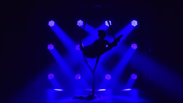 Female Aerial Equilibrium Gymnast Performing Balancing on a Air Silk in a Dark Studio with Blue alt