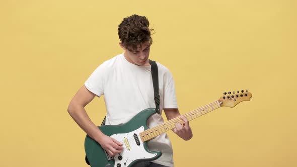 Portrait of Attractive Male Musician with Curly Hair Masterly Playing Electric Guitar at Show or alt
