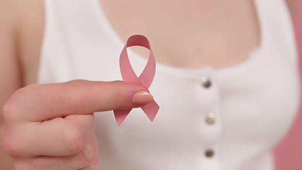 Close Up, Woman Holding Symbolic Pink Ribbon, Brest Cancer Awareness and Hope Concept alt