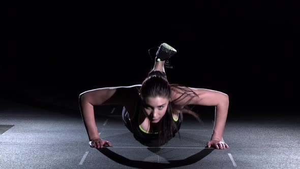 Young Woman Doing Push-ups on Her Knees in a Gym, on Black alt
