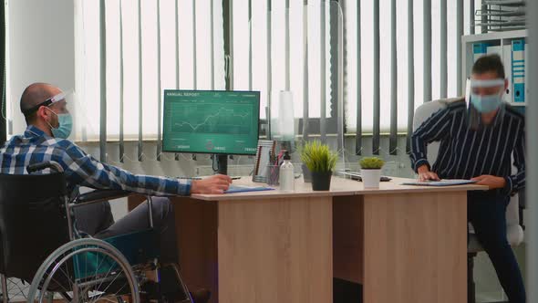 Businessman with Mask Moving with Wheelchair in Workplace alt