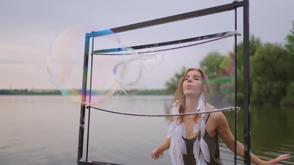 A Young Female Artist Blows a Lot of Soap Bubbles Shows a Theatrical Show Using a Frame in Slow alt