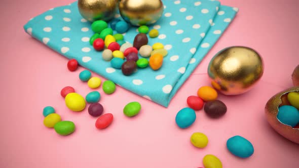 Golden Eggs with Scattered Sweets for Easter on Pink Background