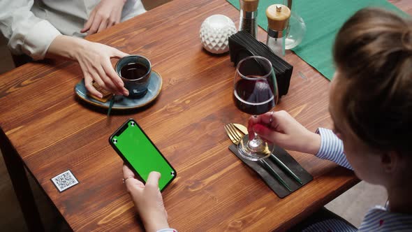Woman Using Smartphone with Chroma Green Screen and Drinking Red Wine Qr Code with Online Menu in alt