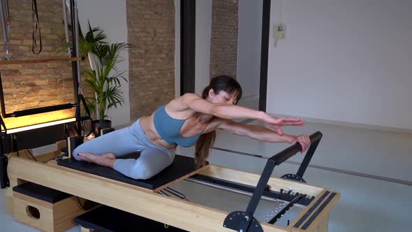 Woman stretching legs on pilates reformer alt