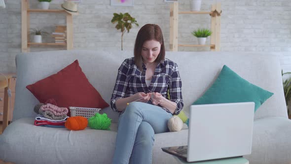 Woman Sitting on the Couch in Front of a Laptop Learning To Knit alt