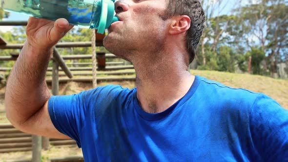 Fit man drinking water after workout during obstacle course alt