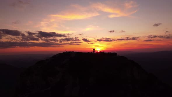 Silhouette of a Person on Top of a Mountain at Sunset Colorfull Clouds Sky