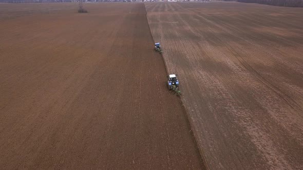 Agricultural Work in the Field, Two Blue Tractors Plow the Land