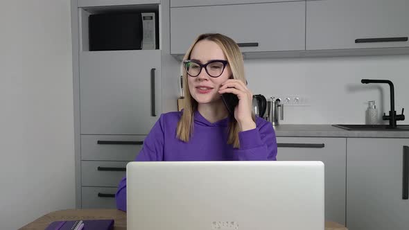 Young Adult Woman in Violet Hoodie Speaks on a Cell Phone and Using Laptop alt