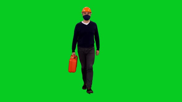 Contractor In Mask And Hardhat Walking With Red Suitcase on Green Screen