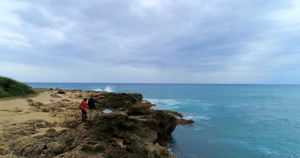 Couple standing on the rocky sea coast 4k alt
