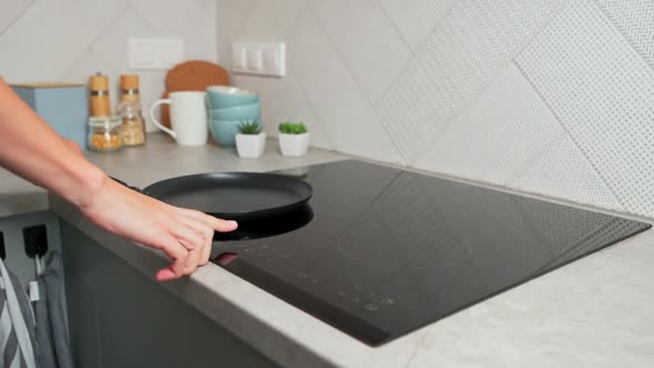 Woman Hand Turns on Modern Induction Stove in the Kitchen alt