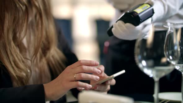 Female Hands Paying Bill By Mobile Phone at Restaurant. Mobile Payment in Cafe alt
