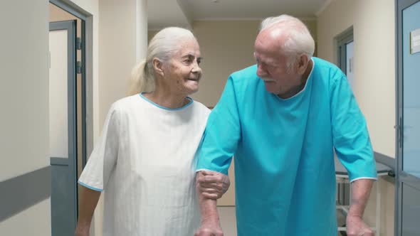 Old woman walking through hospital corridor near old man