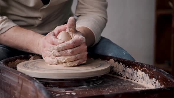 Tradesman Sculpts Pottery on Spinning Potter's Wheel in Workshop Closeup.