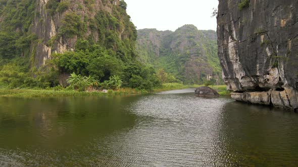 Aerial Shot of Beautiful Limestone Mountains with Passes Carved By a River in Ninh Binh Region a alt