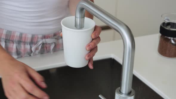 Woman in Kitchen Using Tap