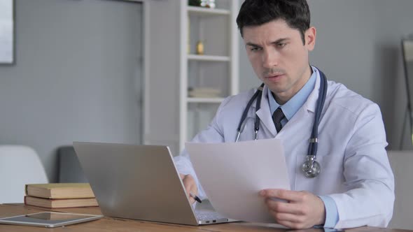 Doctor Working on Medical Report of Patient on Laptop alt