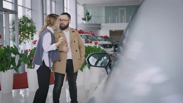 Husband and Wife Choose a New Car in the Showroom of an Official Dealer alt