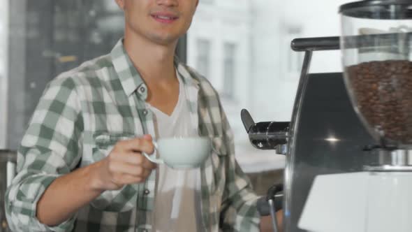 Happy Male Barista Smiling Holding Out Cup of Tasty Coffee To the Camera