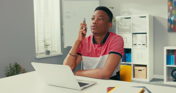 An Employee of a Telemarketing Agency Sits at a Desk in Front of a Laptop Dials a Number to a Client alt