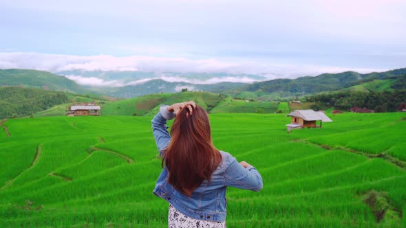 Young woman traveler on vacation looking at beautiful green rice terraces field