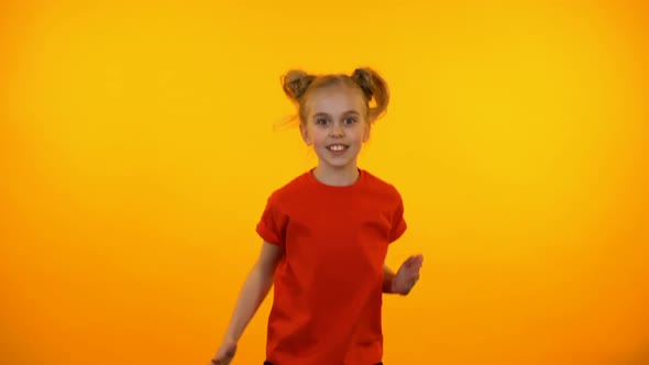 Funny Preteen Girl Dancing to Music, Active Child Having Fun, Orange Background alt