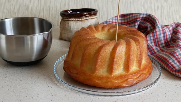 Pouring the syrup over the rum baba. Rum-soaked circular cake