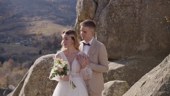 Happy Newlyweds Hugging on Top of the Mountain alt