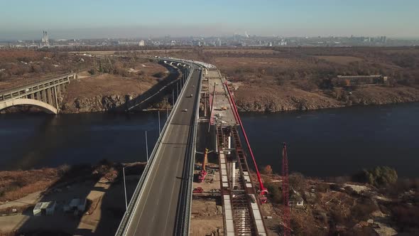 Construction of a bridge across the river. Heavy traffic on the bridge. View from the top. alt