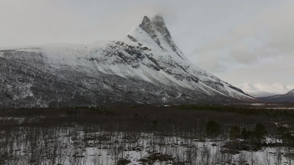 Flying over the forest towards the snow covered Otertinden mountain in northern Norway. 4k drone sh alt
