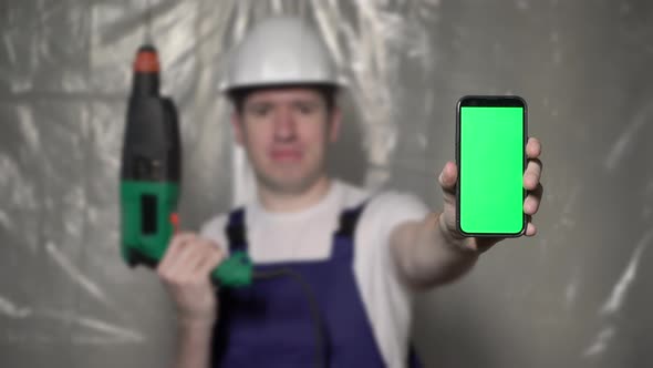 Builder in Blue Overalls and White Hard Hat Hold Mobile Phone Green Screen