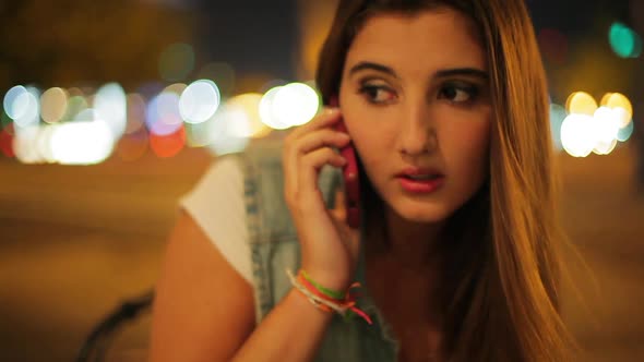 Teenage girl talking on cell phone outdoors at night