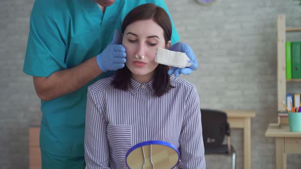 Man Doctor Plastic Surgeon Removes Bandage From Woman's Face After Surgery alt