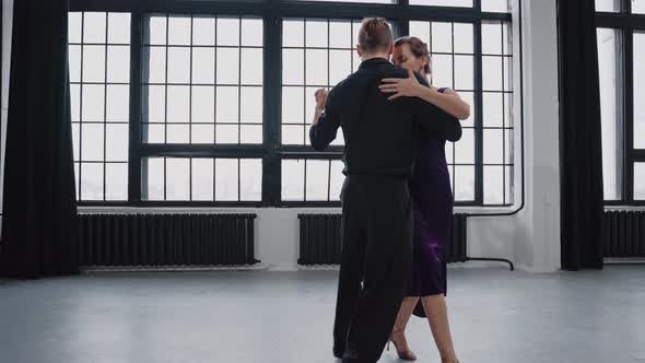 Shot of a Pair Sensually Dancing a Tango Against the Background of Large Windows