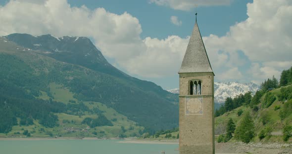 Medium Shot, Scenic view of Kirchturm von Altgraun in Italy, Reschensee and mountain range in the ba alt