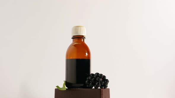 Medicine In A Jar On A Turntable On A White Background, A Bottle Of Medicine From A Black Berry. alt