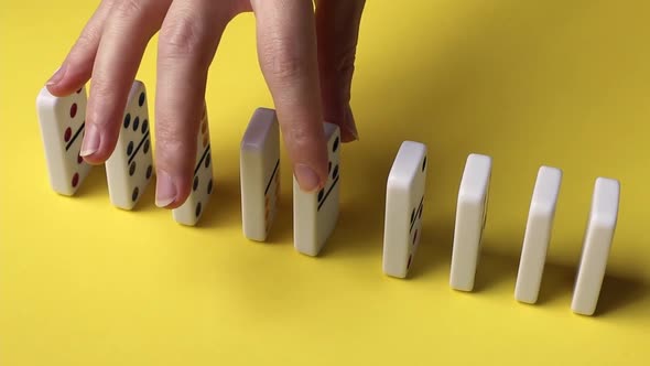 The hands of a young caucasian woman put dominoes in a row. alt