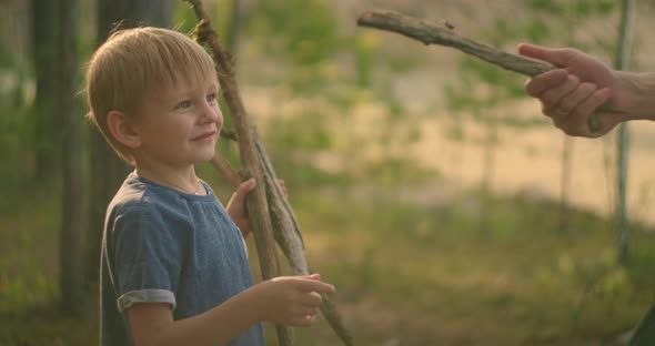 The Boy Collected Sticks in the Woods and Gave His Father a Stick Gun From a Tree. Show the Find alt