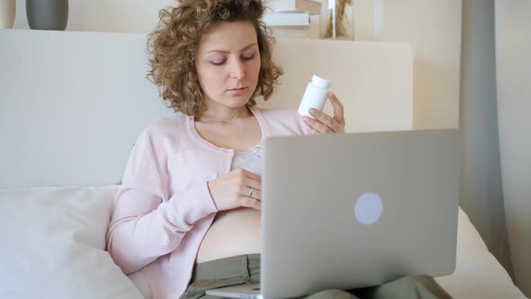 Pregnant Woman Checking Medicine Using Laptop Computer. Vitamins And Nutrition In Pregnancy. alt