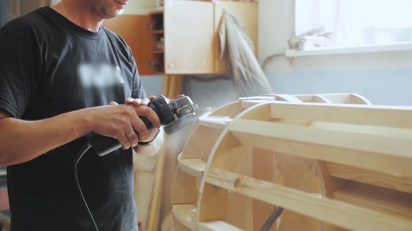 A Professional Carpenter Working with Wood on a Woodworking Machine Grinds and Polishes Wood alt