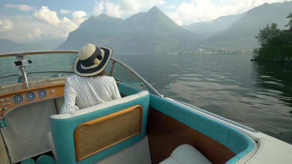 A woman on a classic luxury wooden runabout boat on an Italian lake. alt
