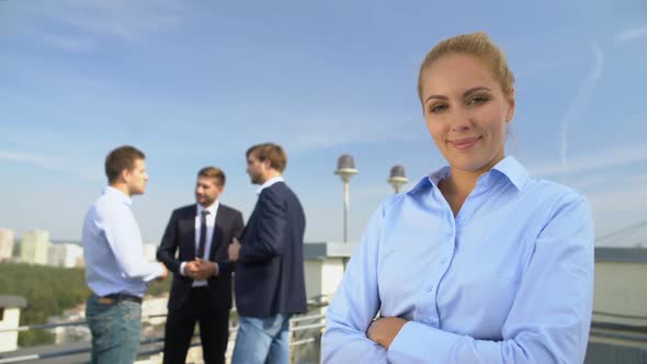 Successful Lady Boss Smiling on Camera Outdoors, Male Colleagues Background