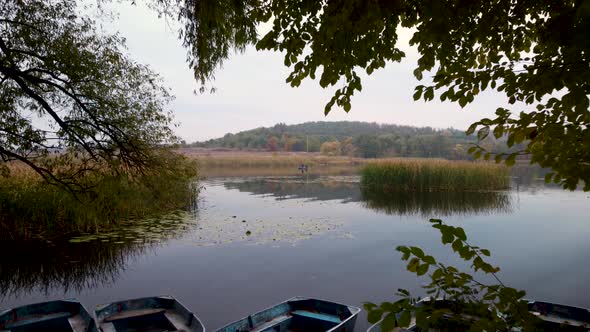 landscape river with an old boat mooring. Two fishermen in a boat. autumn. aerial drone shot. alt